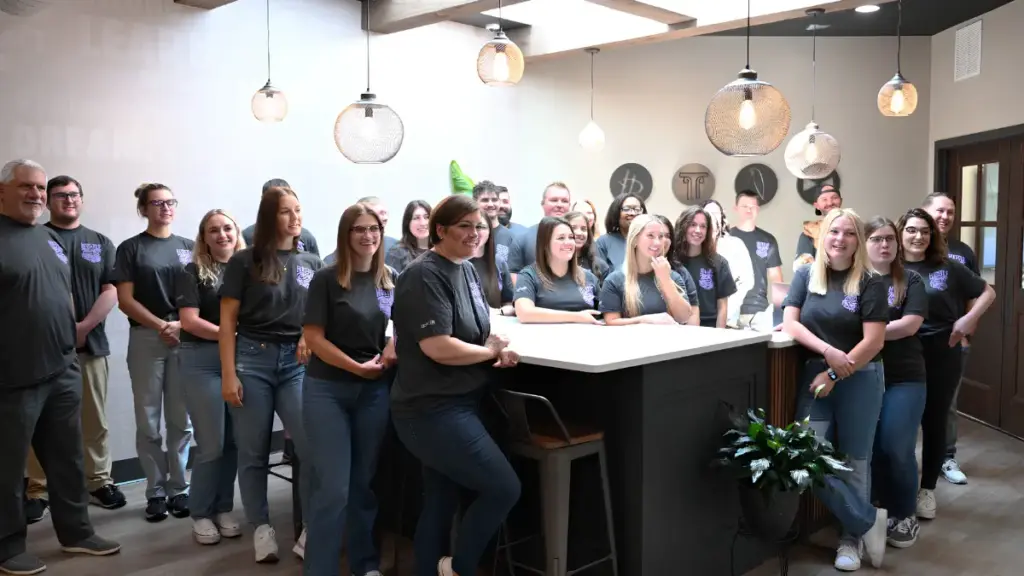 Group photo of the HD Growth Partners team smiling in an office breakroom setting.